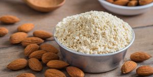 almond flour in bowl and almonds on wooden table