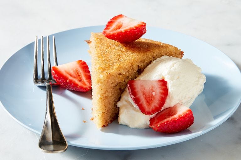 slice of almond cake with whipped cream and strawberries on a blue plate
