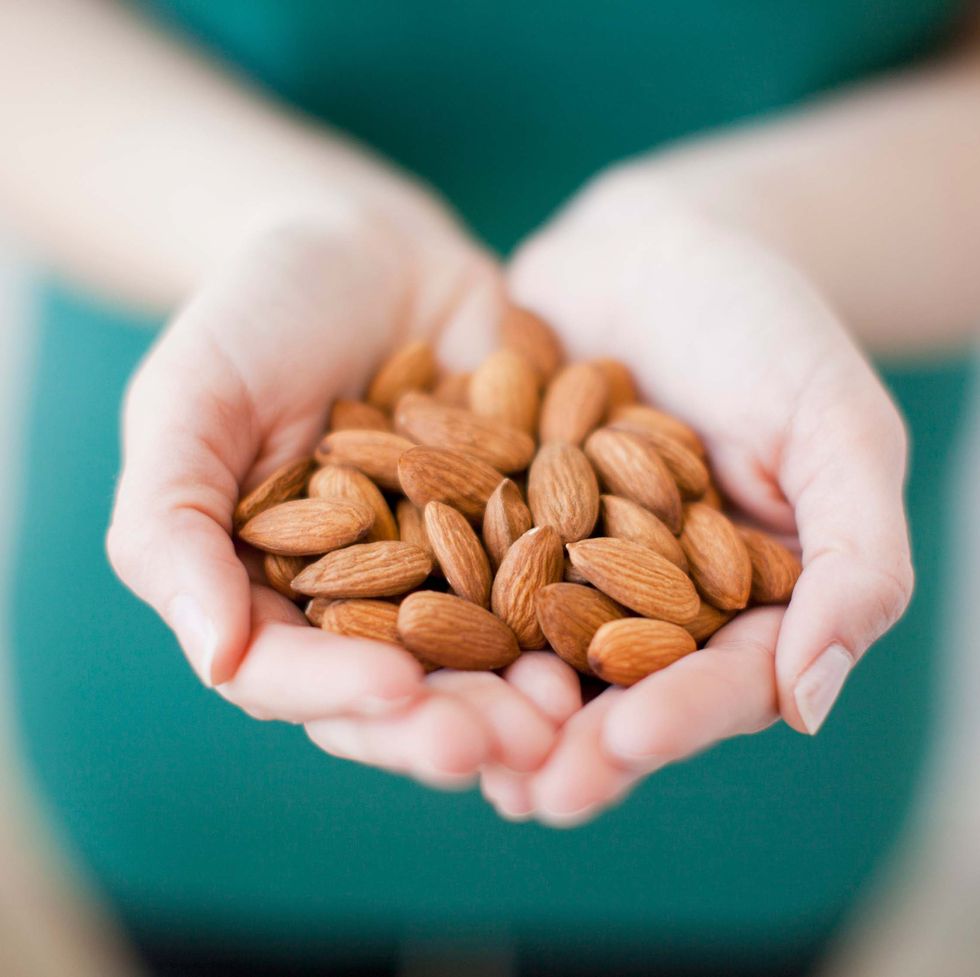 studio shot of woman showing handful of almonds