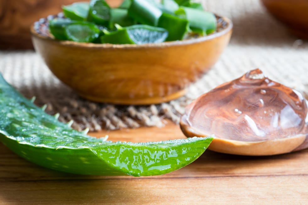 Aloe vera leaf, with aloe vera gel and slices in the background