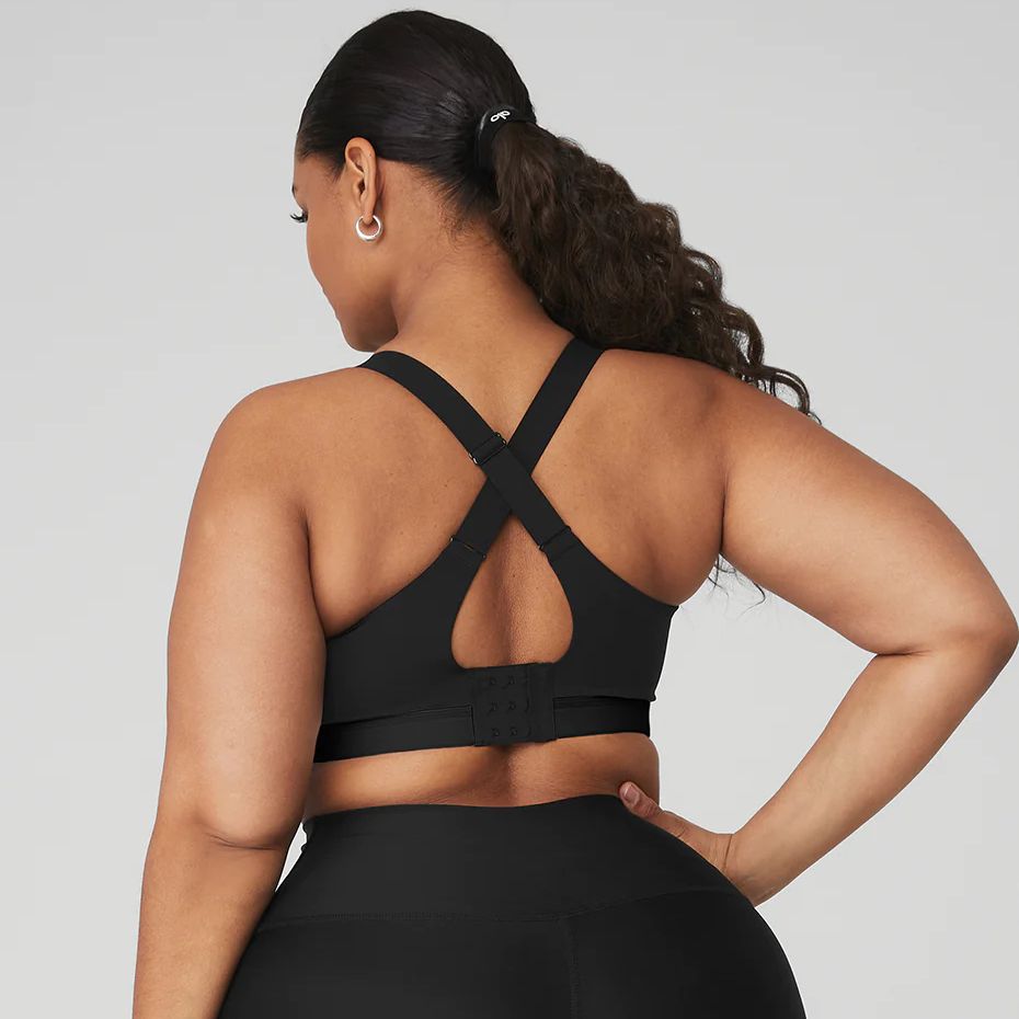 a model wearing a black sports bra by alo in front of a plain backdrop in a roundup of the best sports bras for women 2023