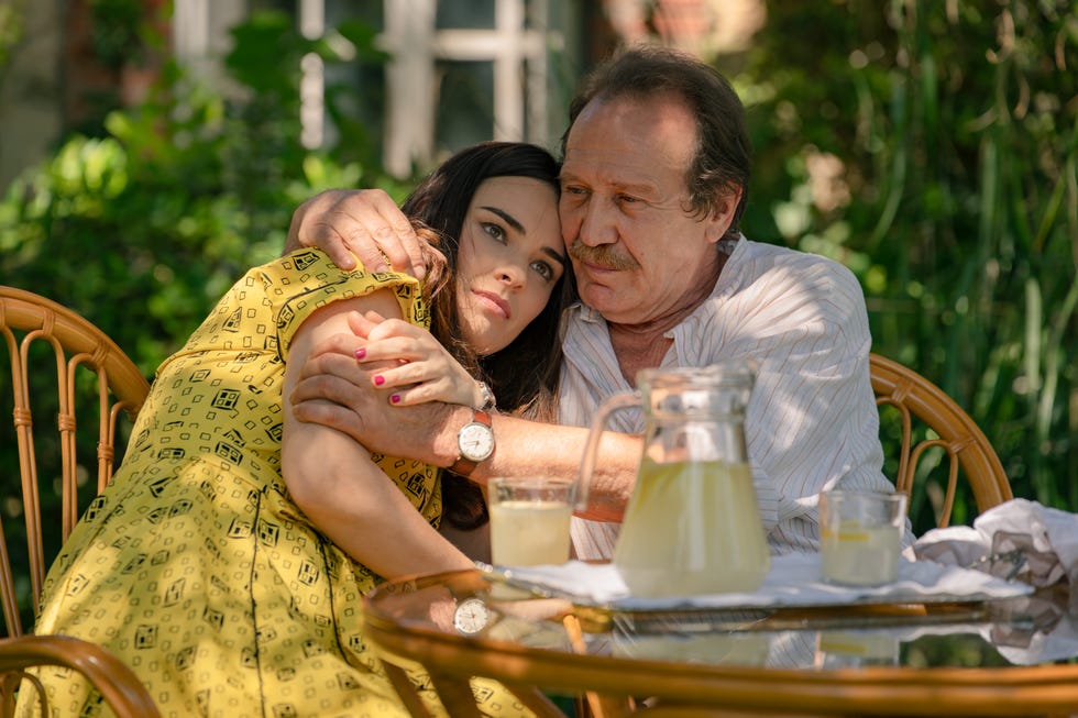 Two individuals sharing an affectionate moment outdoors at a table