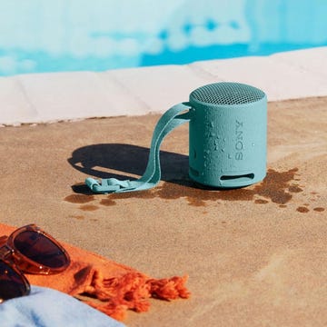altavoz bluetooth un altavoz bluetooth sony srs xb100 en el bordillo de una piscina junto a unas gafas de sol y una toalla naranja