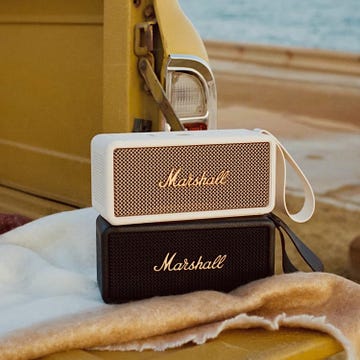 dos altavoces marshall middleton sobre una manta en el maletero de una ranchera amarilla junto a la playa