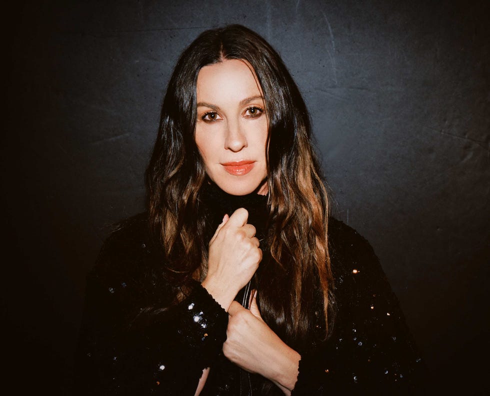 a person holding a black handbag wearing a black sequined outfit with a dark background