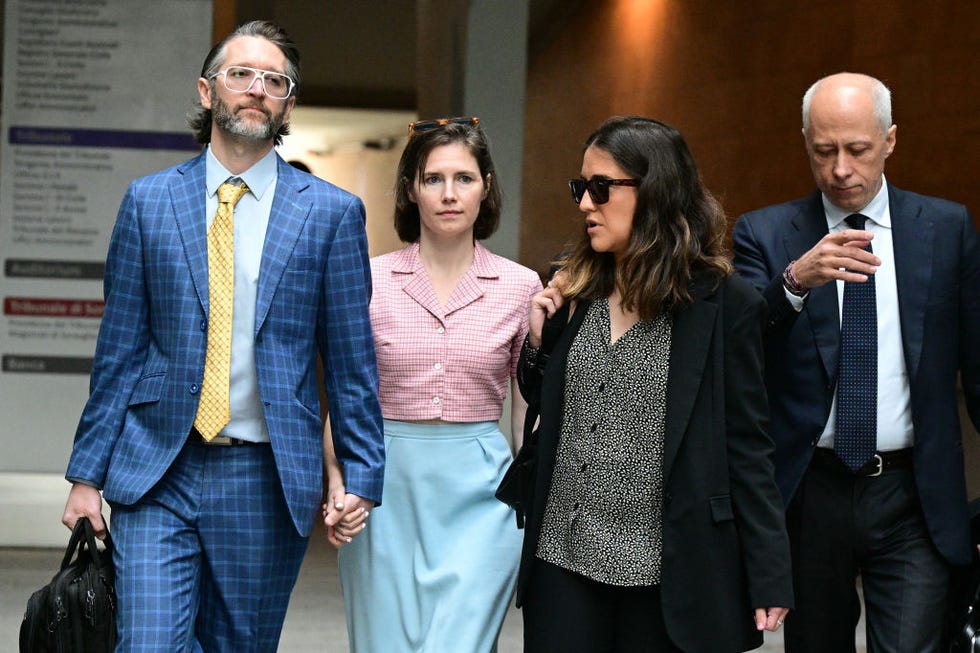amanda knox holds hands with a man in a blue plaid suit, a woman and another man in a suit walk on the right