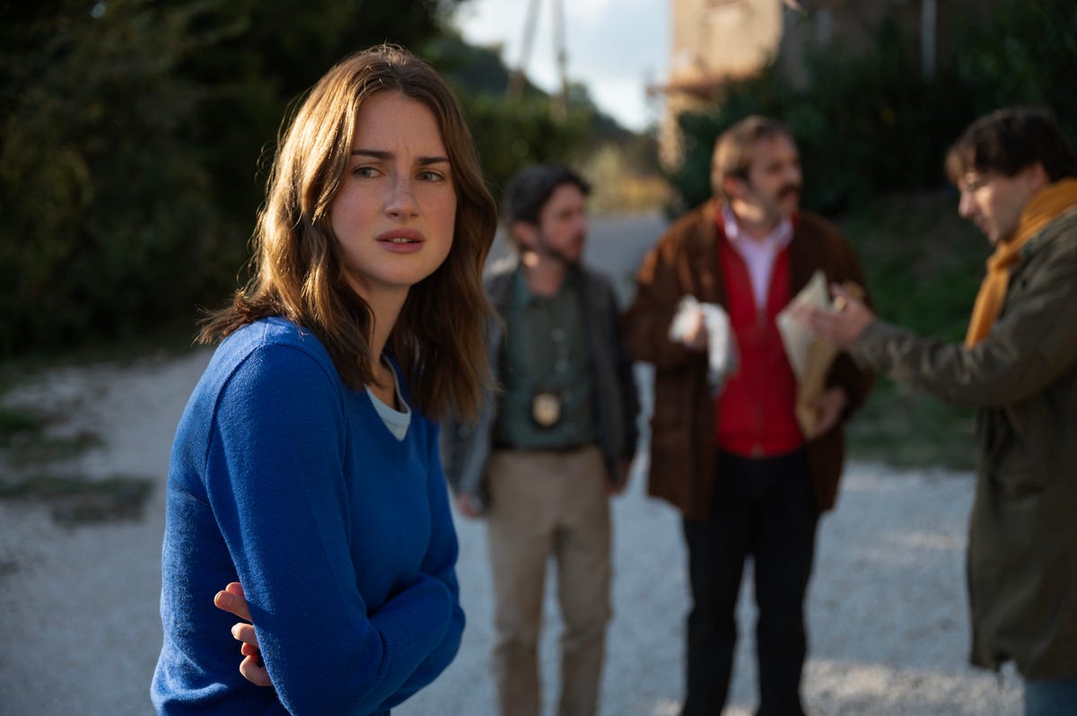 young woman looking past frame nervously as people speak in the background