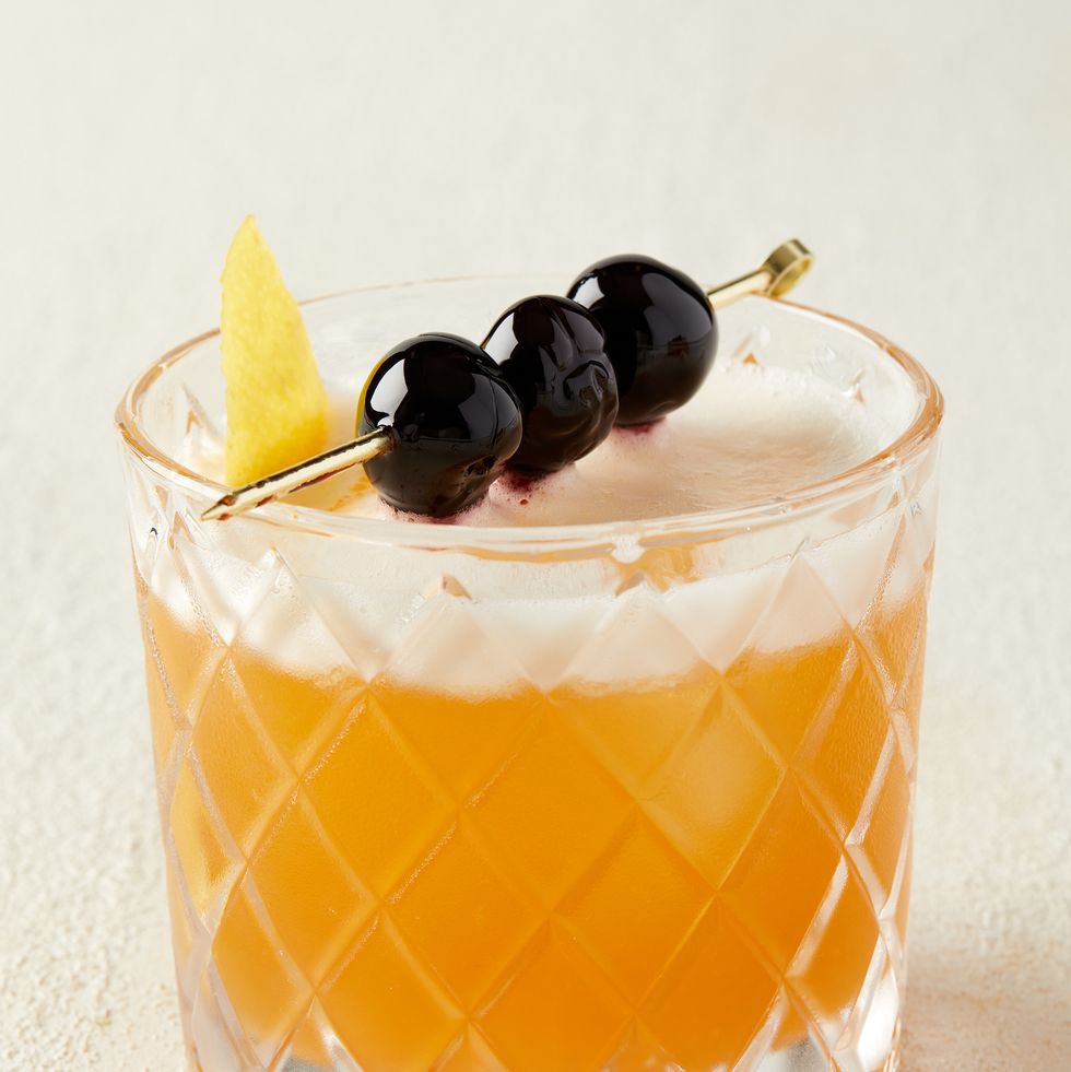 amaretto sour garnished with lemon peel and three cherries