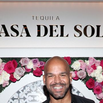 amaury nolasco wears a black outfit and poses in front of a flower wall in december 2021