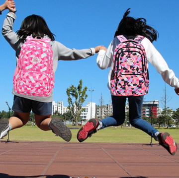 group of children jumping together while holding hands each wearing a colorful backpack group of children jumping together while holding hands each wearing a colorful backpack
