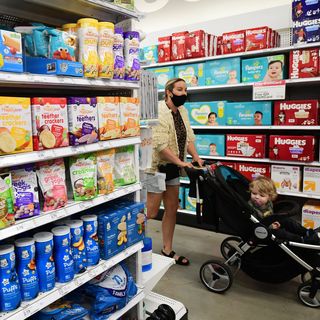 woman pushing stroller on baby aisle in store