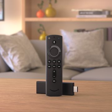 amazon fire tv stick 2020 shown with alexa voice remote on a table in front of a grey sofa