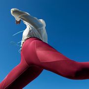 woman jumping in red leggings against blue sky