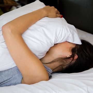 woman holding pillow over her body and face