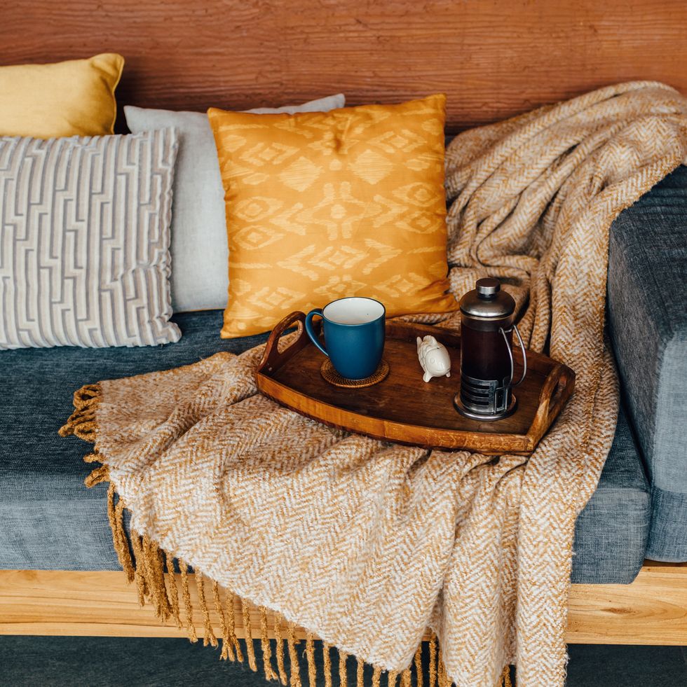 serving tray with tea on gray sofa with yellow and orange pillows and wool blanket warm and cozy weekend at home modern and fresh living space top view