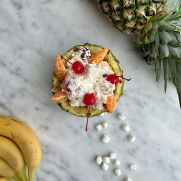Fruit salad served in a pineapple bowl with bananas and marshmallows nearby fruit salad served in a pineapple bowl with bananas and marshmallows nearby