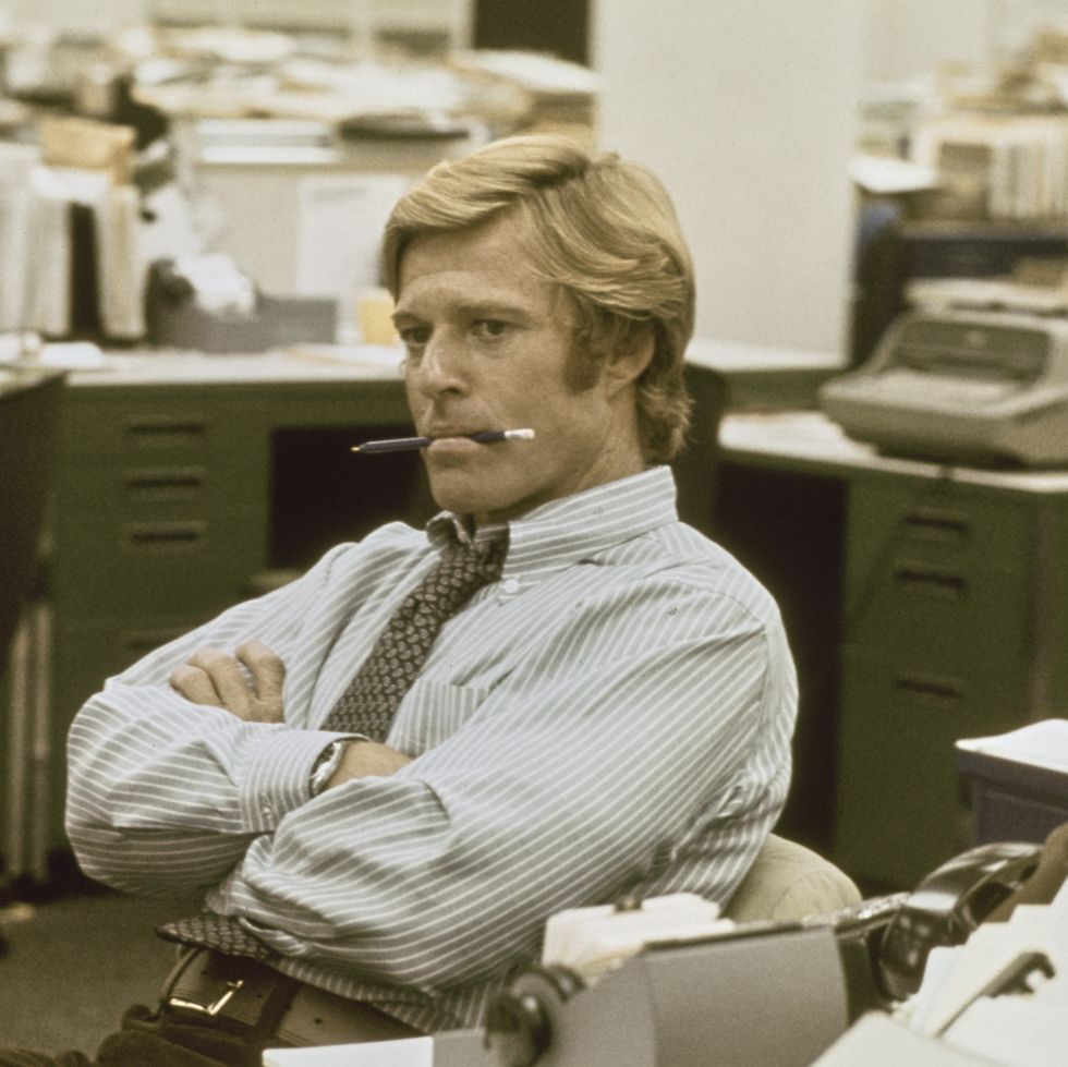american actor robert redford wearing a blue and white striped shirt with a patterned tie, his arms folded with a pencil in his mouth, in a recreation of the washington post's offices in 'all the president's men', filmed at burbank studios in burbank, california, 1976. the political thriller based on the watergate scandal, directed by alan j pakula, starred redford as bob woodward. (photo by michael ochs archives/getty images)