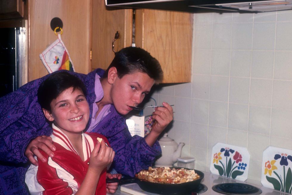 joaquin and river phoenix standing next to a stove cooking food and smiling for the camera