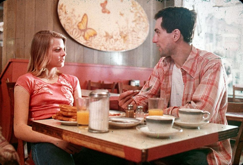 jodie foster as iris and robert de niro as travis bickle in taxi driver sitting at a diner table