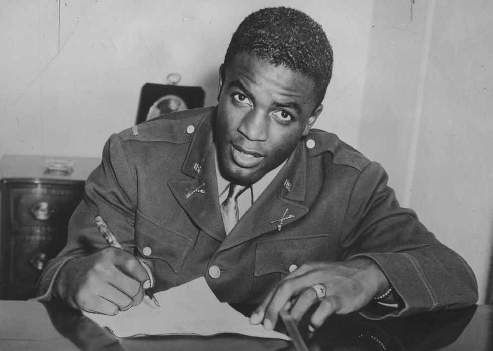jackie robinson looking at a camera while signing papers