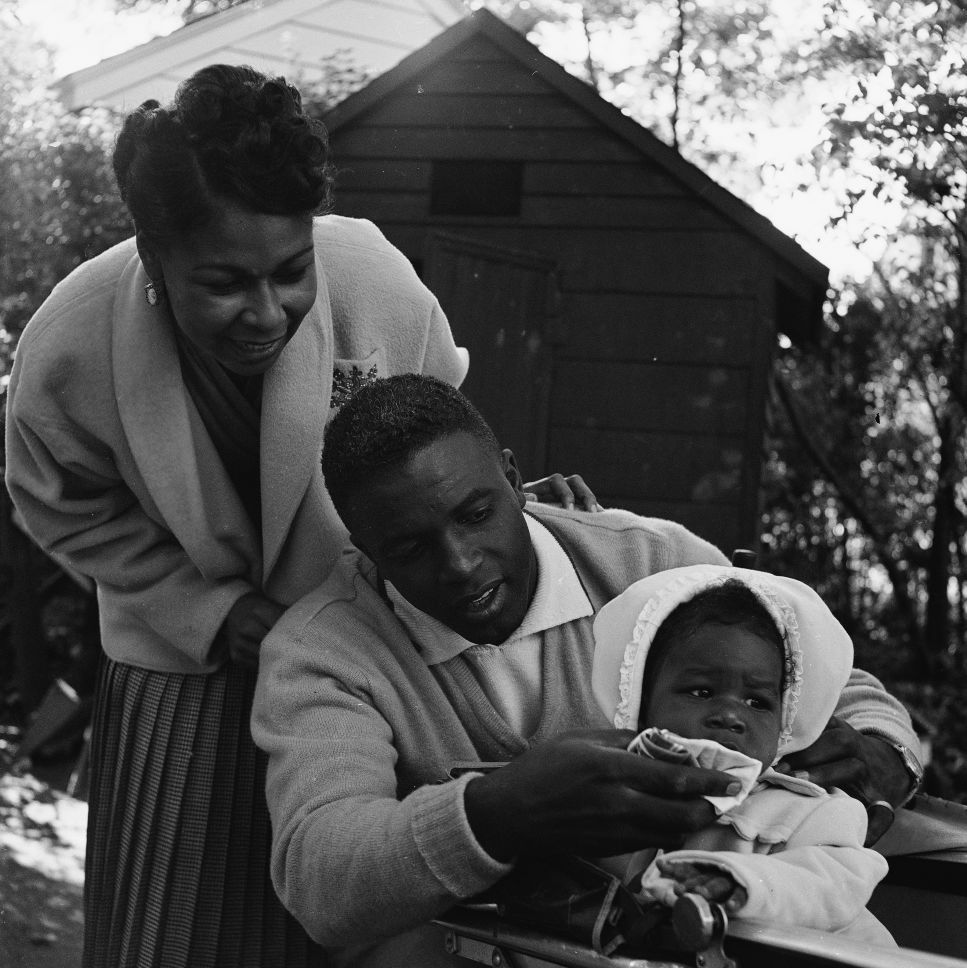 jackie robinson wiping his baby daughters face as wife rachel stands behind them