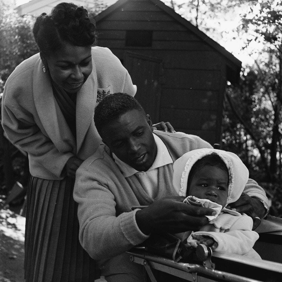 jackie robinson wiping his baby daughters face as wife rachel stands behind them