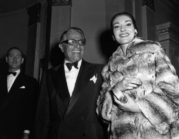 maria callas wearing a fur coat and smiling next to aristotle onassis