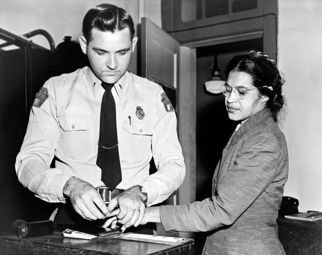 a black and white photograph of rosa parks being fingerprinted by a police officer