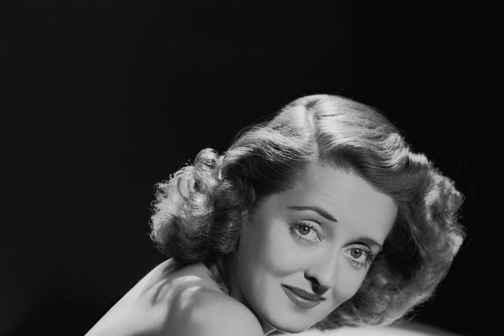 a black and white publicity photo of bette davis looking directly into the camera and smiling