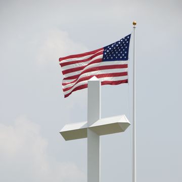 american flag flying behind large white cross