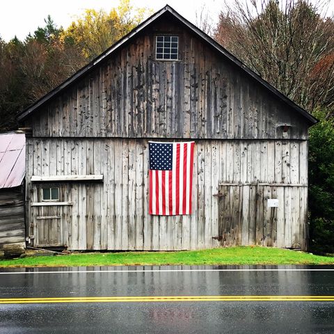 american flag on wooden house by wet road