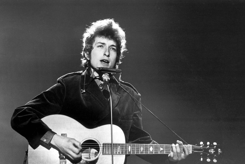 bob dylan plays guitar and sings intro a microphone