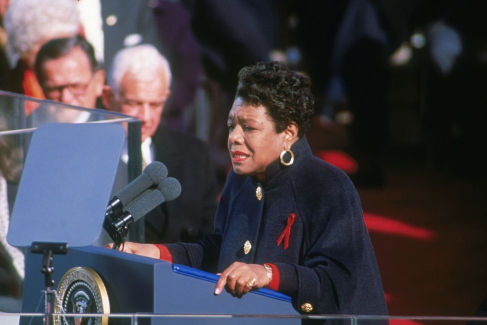 maya angelou standing behind a podium as she reads a poem