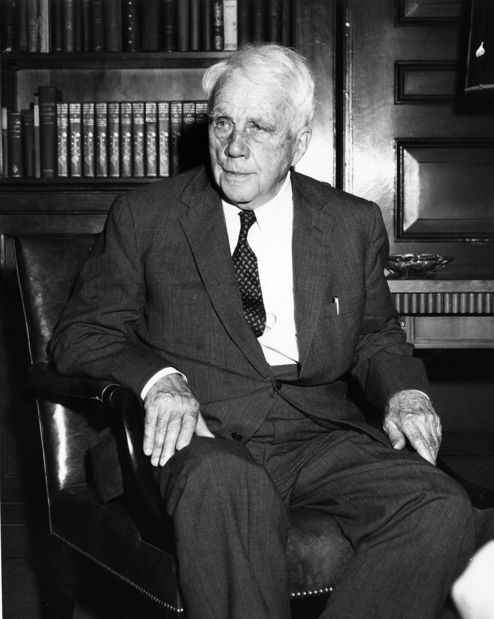 robert frost sitting in a chair in front of a bookshelf