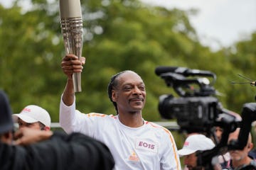 paris 2024 olympic games torch relay in paris, with the torch itself held by a smiling snoop dogg