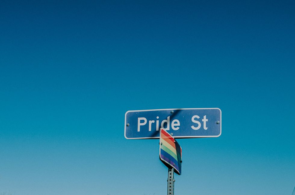 american road sign displaying 'pride street' with a rainbow flag underneath