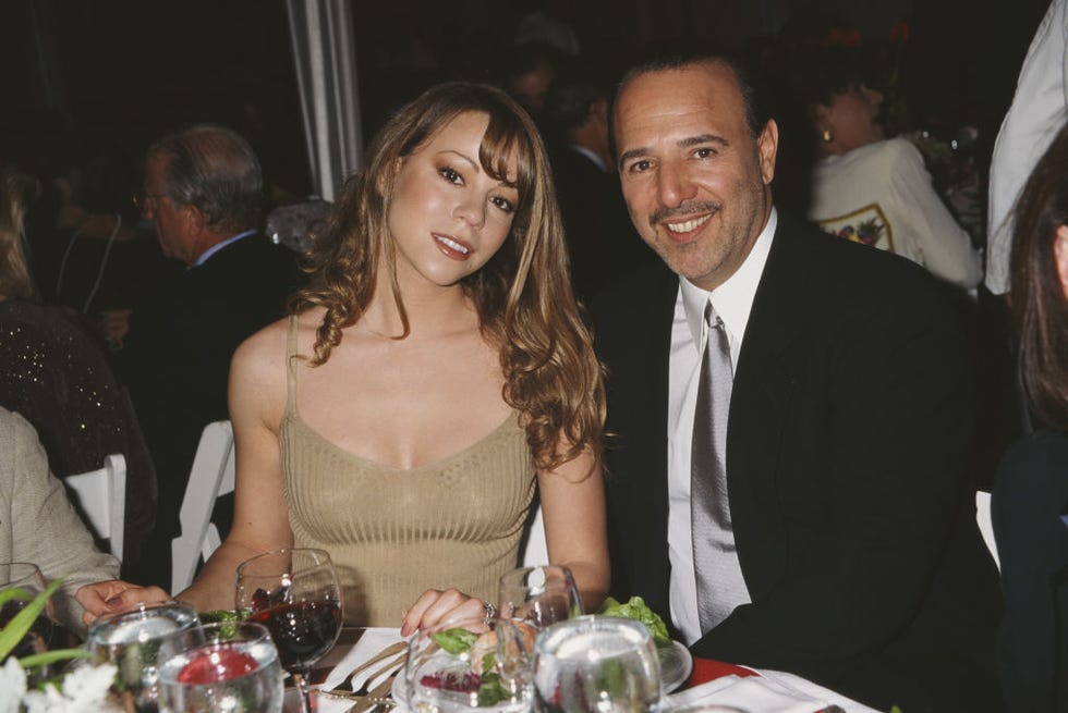 mariah carey and tommy mottola sit at a table and smile at the camera