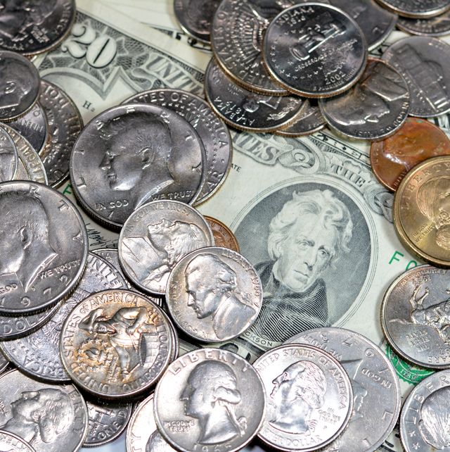 a pile of silver and gold coins over paper banknotes