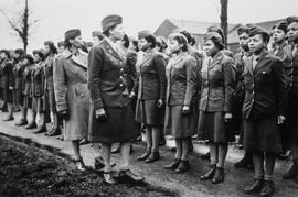 an all female army battalion stands at attention as two officers examine them