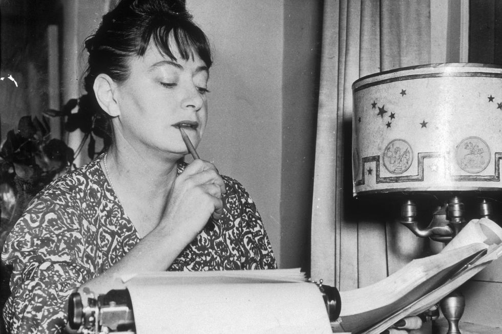 dorothy parker holds a manuscript with a pen in her mouth