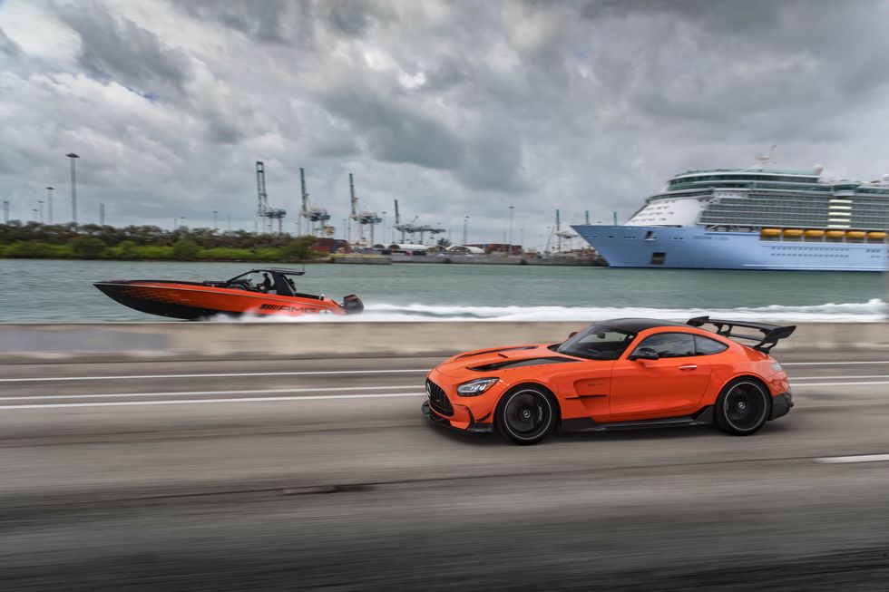 cigarette boat in the water and amg gt black series driving alongside on a causeway