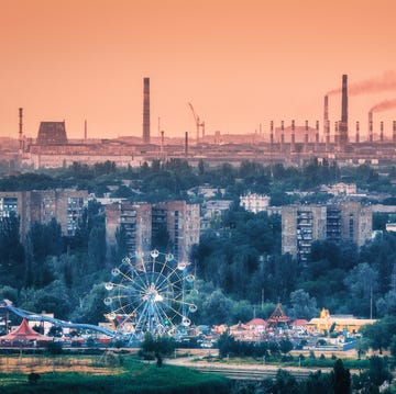 amusement park with ferris wheel and buildings in mariupol, ukraine before war steel plant at sunset steel factory with smokestacks steel works, iron works heavy industry metallurgical combine