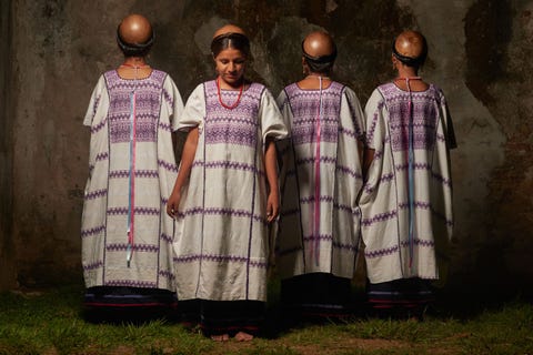 Amuzgovrouwen dragen traditionele huipiljurken en kalebassen op hun hoofd om zich tegen de zon te beschermen en er water uit de rivier mee te drinken
