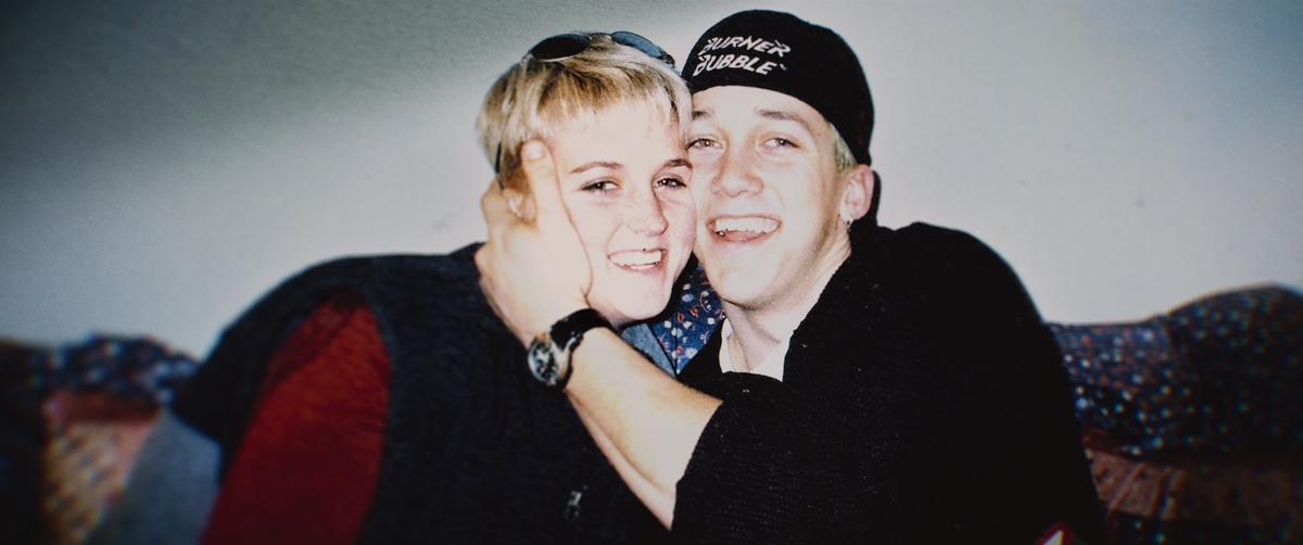 a young man and woman smiling and embracing as they sit on a couch