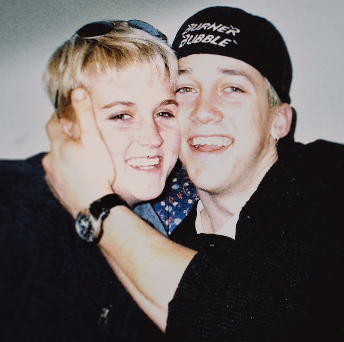 Siblings Amy Bradley and Brad Bradley a young man and woman smiling and embracing as they sit on a couch