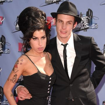 blake fielder civil embracing amy winehouse with his right arm and the two leaning in for a photo at an award show red carpet