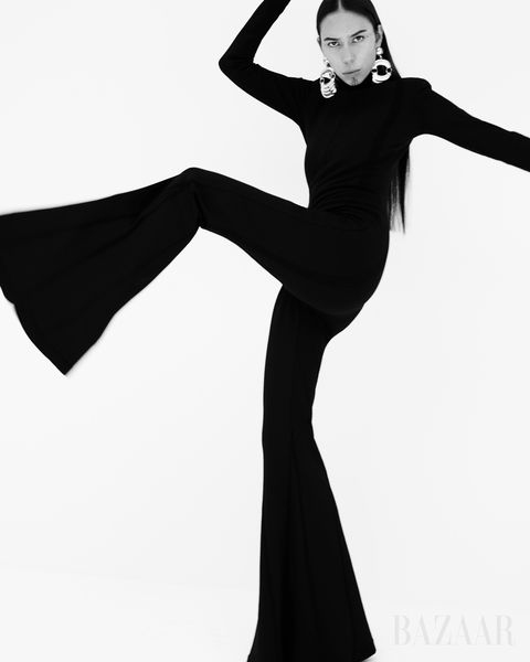 black and white image of woman kicking in black bell bottom jumpsuit