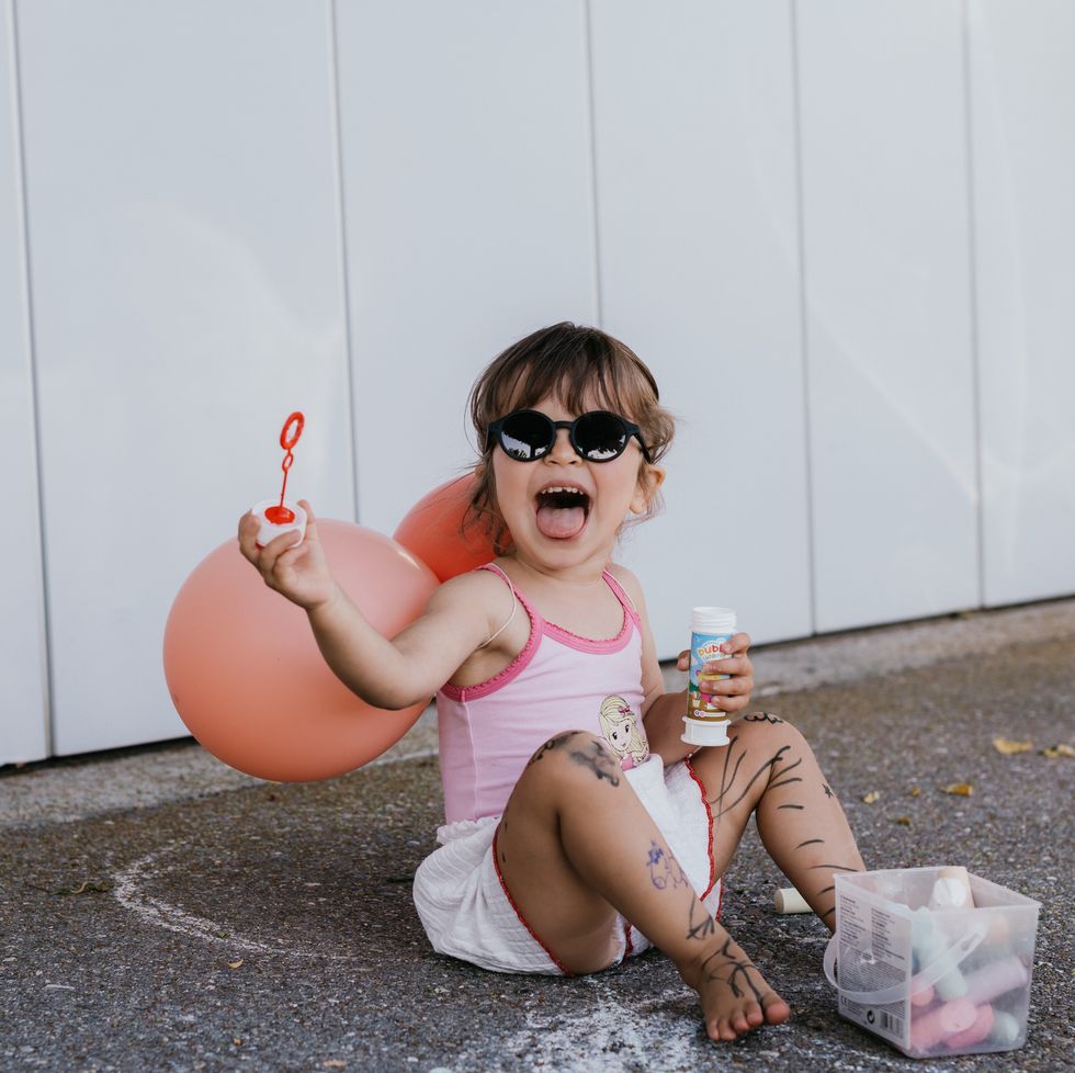 an adorable toddler girl playing with bubbles outside
