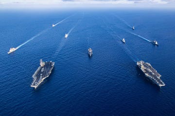 overhead shot of two american aircraft carriers along with fleet of other navy ships