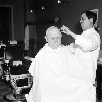 an almost bald man receiving a hair cut in a barber shop ca december 1935